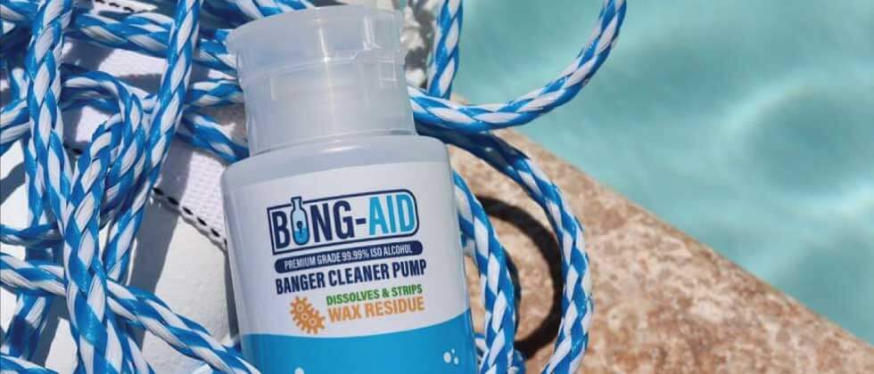 Bong-Aid ISO Pump Bottle sitting on a pool float and blue and white rope next to a pool
